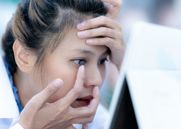 A female ophthalmologist in a ground coat is wearing contact lenses, close-up focusing on face.